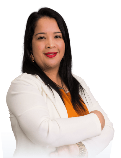 Edilaine (Mulher) veste uma camisa mostarda com um paleto branco por cima, ela esta de perfil, com os bracos cruzados olhando pra frente.